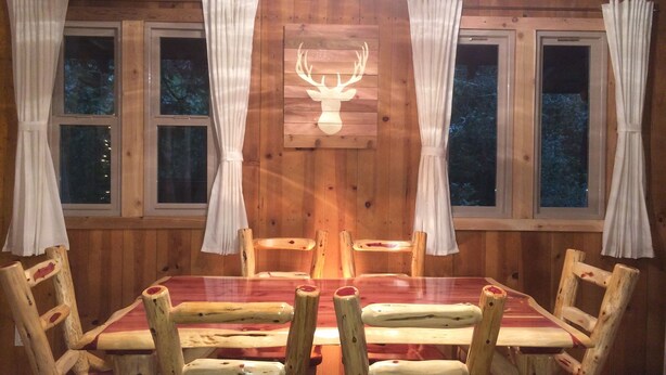 Interior de madeira com uma mesa de jantar, cadeiras e cortinas.