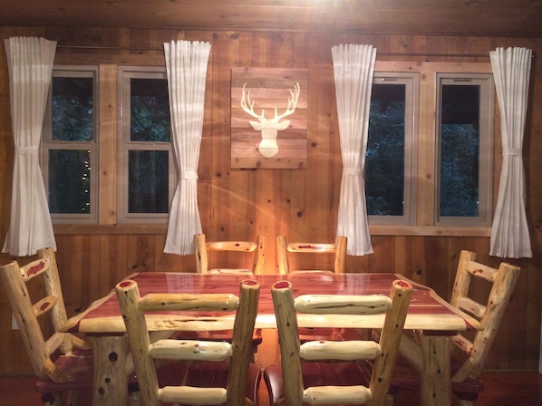 Ein Holzinterieur mit einem Esstisch, Stühlen und Vorhängen.