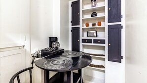 A compact kitchen with a black table, white cabinets, and a coffee machine.