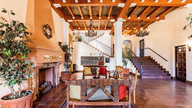 A spacious lobby with a fireplace, a wooden bench, and a staircase leading to upper floors.