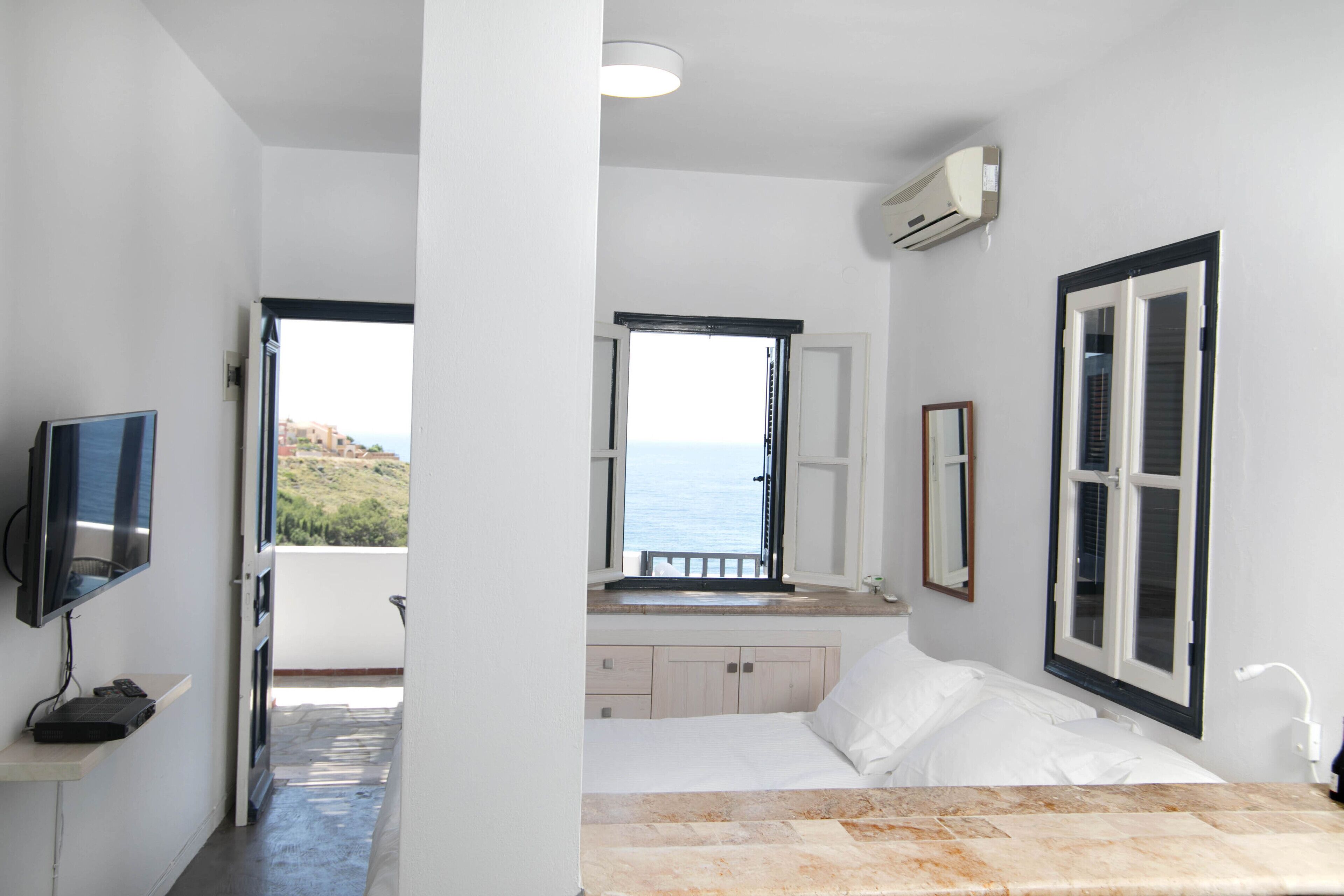 Ein Schlafzimmer mit Bett, Fernseher, Fenster mit Blick und Klimaanlage.