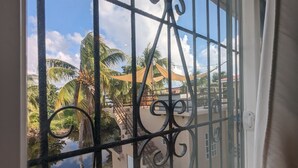 Een balkon met ijzeren hekwerk, uitzicht op palmbomen en een heldere lucht.