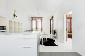 Una cocina moderna con armarios blancos, un microondas y un comedor con un tapete negro.