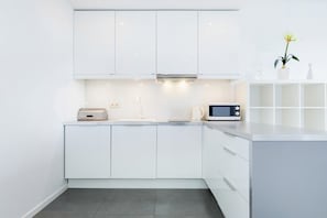A modern kitchen with white cabinetry, a microwave, and a toaster.