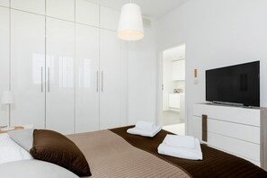 A modern hotel room with a bed, a TV, and a wardrobe.
