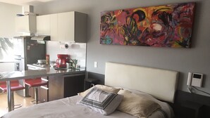 A modern bedroom with a large bed, a small kitchenette, and a colorful abstract painting on the wall. - FLAT CHAPINERO CENTRAL (Bogotá)