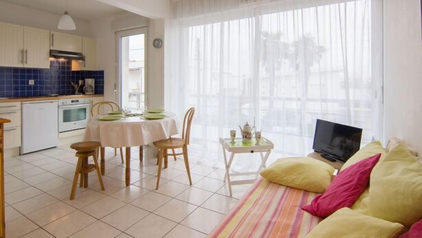Un espacio habitable compacto con comedor, kitchenette y sofá con cojines.
