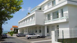 Un edificio moderno de dos pisos con techo plano, ventanas amplias y un balcón en el piso superior.