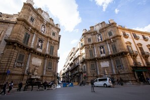 A street with historic buildings, a horse-drawn carriage, and a white van.