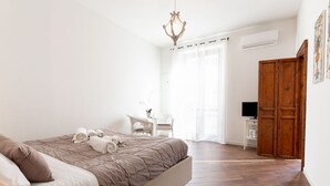 Ein Schlafzimmer mit Bett, Schreibtisch, Fernseher und Kleiderschrank.