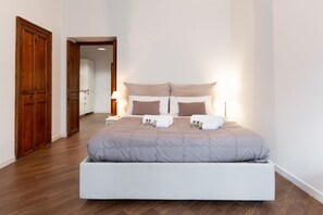 A bedroom with a bed, bedside lamps, and a wooden door.
