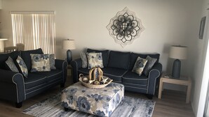 A living room with two dark sofas, a coffee table, and a decorative wall piece.