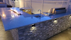 Una cocina al aire libre con protector mural de piedra, electrodomésticos de acero inoxidable y un lavamanos.