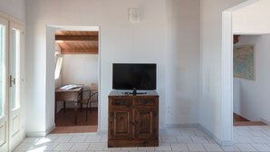 A room with a wooden cabinet, a television, and a door leading to another room. - Aretusa Apartment with Terrace by Wonderful Italy (Siracusa)