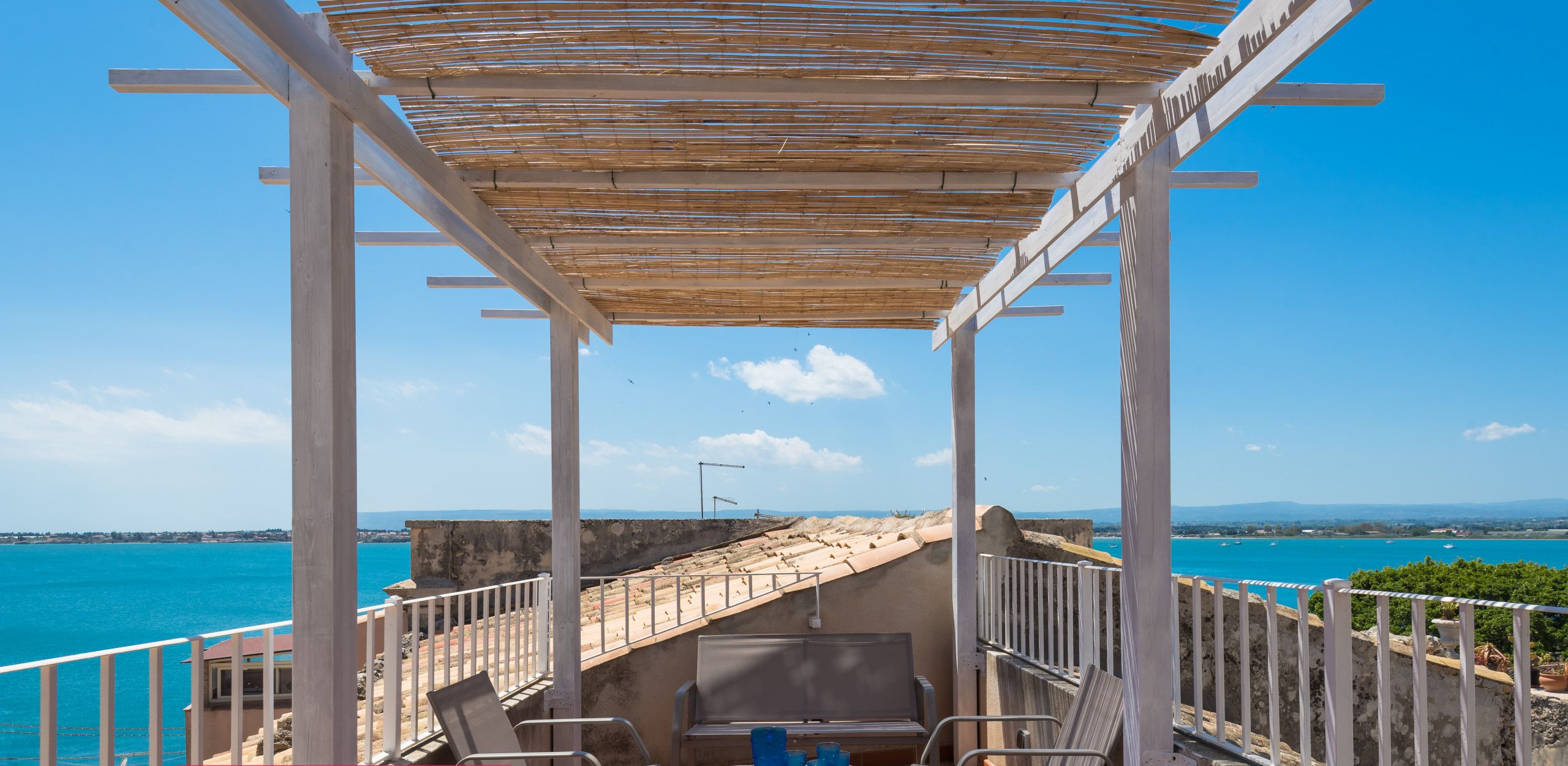 Un balcon avec vue sur la mer, une table avec des chaises et une pancarte indiquant « ESPACE DE TRAVAIL CONNECTÉ ».