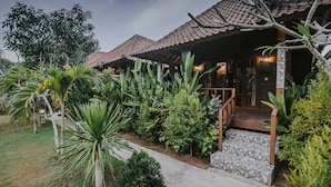 A villa with a tiled roof, a stone pathway leading to the entrance, and lush tropical vegetation surrounding the property. - Nerima Hut Lembongan (Lembongan Island)