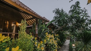 A wooden building with a tiled roof, surrounded by lush greenery and a concrete pathway. - Nerima Hut Lembongan (Lembongan Island)