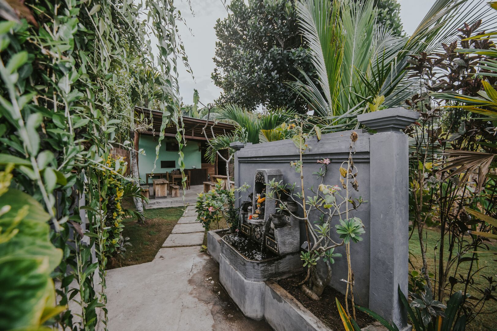 Un giardino con un sentiero che conduce a un edificio dalla facciata verde.