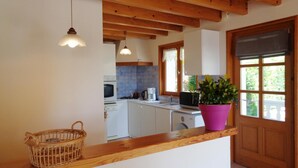 A kitchen with wooden beams, a wooden countertop, a basket, and a potted plant. - Traditional cottage with terrace, pets allowed (La Tuilière)