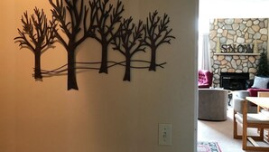 Un mur orné d’un décor en forme d’arbre métallique et une cheminée en pierre sur laquelle est inscrit le mot « NEIGE ».