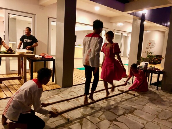 A group of people in a well-lit indoor space with a tiled floor, a table with food, and a doorway leading to another room. - Sunset Cove Beach & Dive Resort (Romblon)