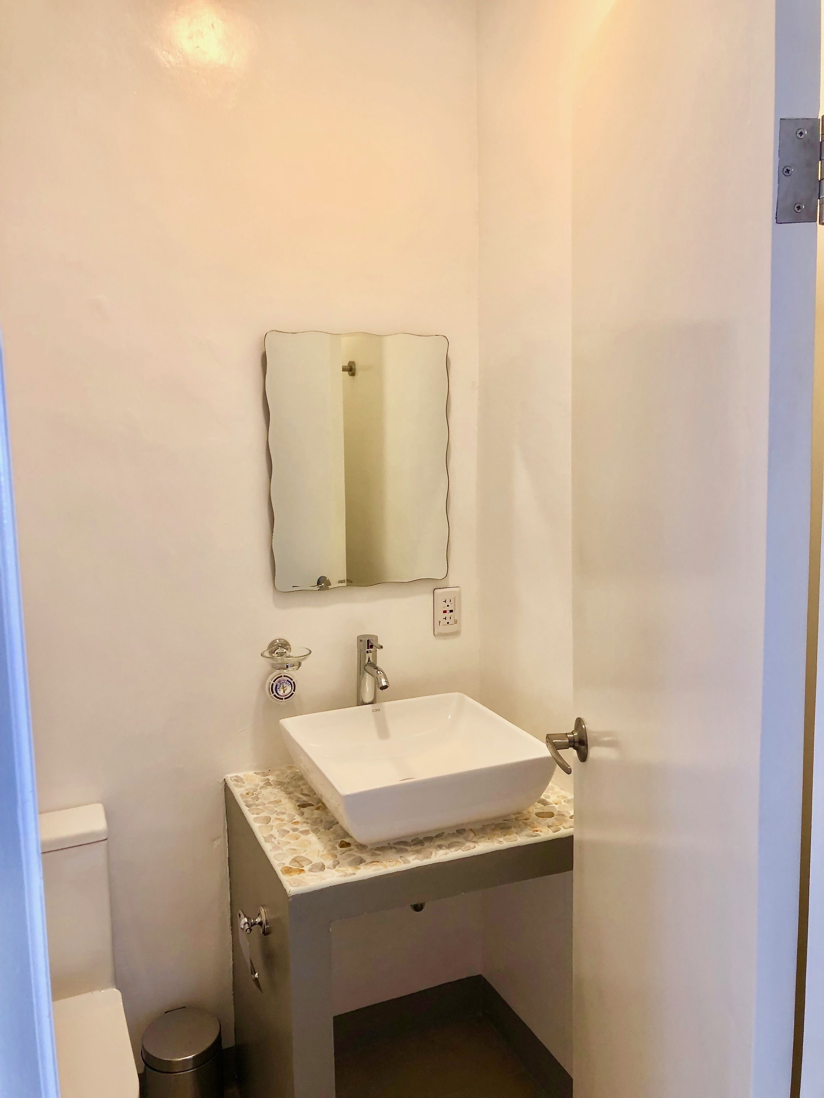 A small bathroom with a white sink, a mirror, and a toilet.