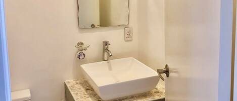 A small bathroom with a white sink, a mirror, and a toilet.