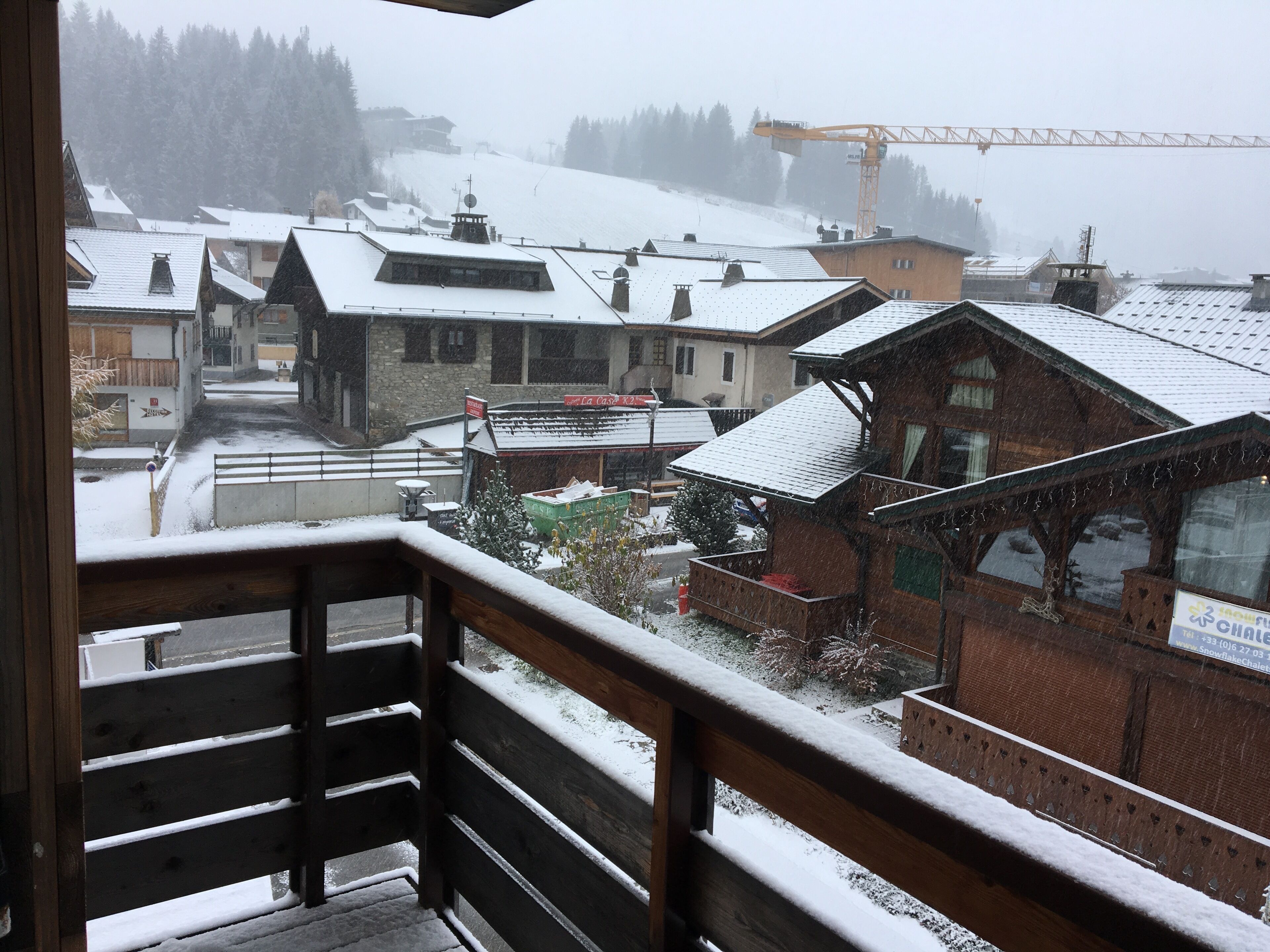Ein verschneites Dorf mit Holzhäusern und einem sichtbaren Baukran.