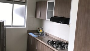 A compact kitchen with a gas stove, a sink, and wooden cabinets. - APTO  LOFT   PEREIRA (Pereira)