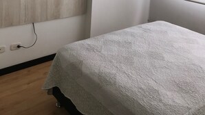 A bedroom with a bed, a mounted TV, an air conditioning unit, and a window. - APTO  LOFT   PEREIRA (Pereira)