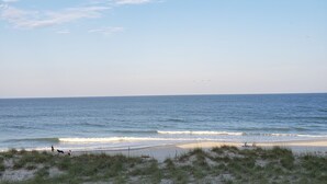 Ein Strand mit einer Holzbrüstung, grasbewachsenen Dünen und dem Meer.
