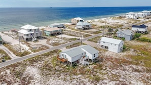 Una zona residencial costera con casas sobre pilotes, una carretera y una playa.