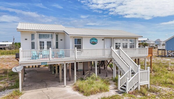 Une maison située en bord de mer, dotée d’une terrasse, d’une enseigne indiquant « SURF’S SAFARI » et du numéro « 5939 » sur la façade.