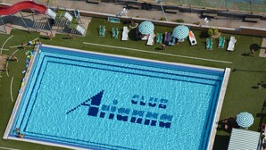 Ein Swimmingpool mit Club Aruba Logo, umgeben von Liegestühlen und einer Rutsche.