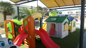 Ein Kinderspielbereich mit Rutschen und einer kleinen Hauskonstruktion.