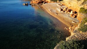 Un paysage côtier caractérisé par une eau limpide, des falaises rocheuses et une végétation clairsemée.