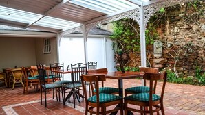 An outdoor patio with a covered seating area, stone walls, and a decorative white railing. - 137 High Street Guest House (Makhanda)