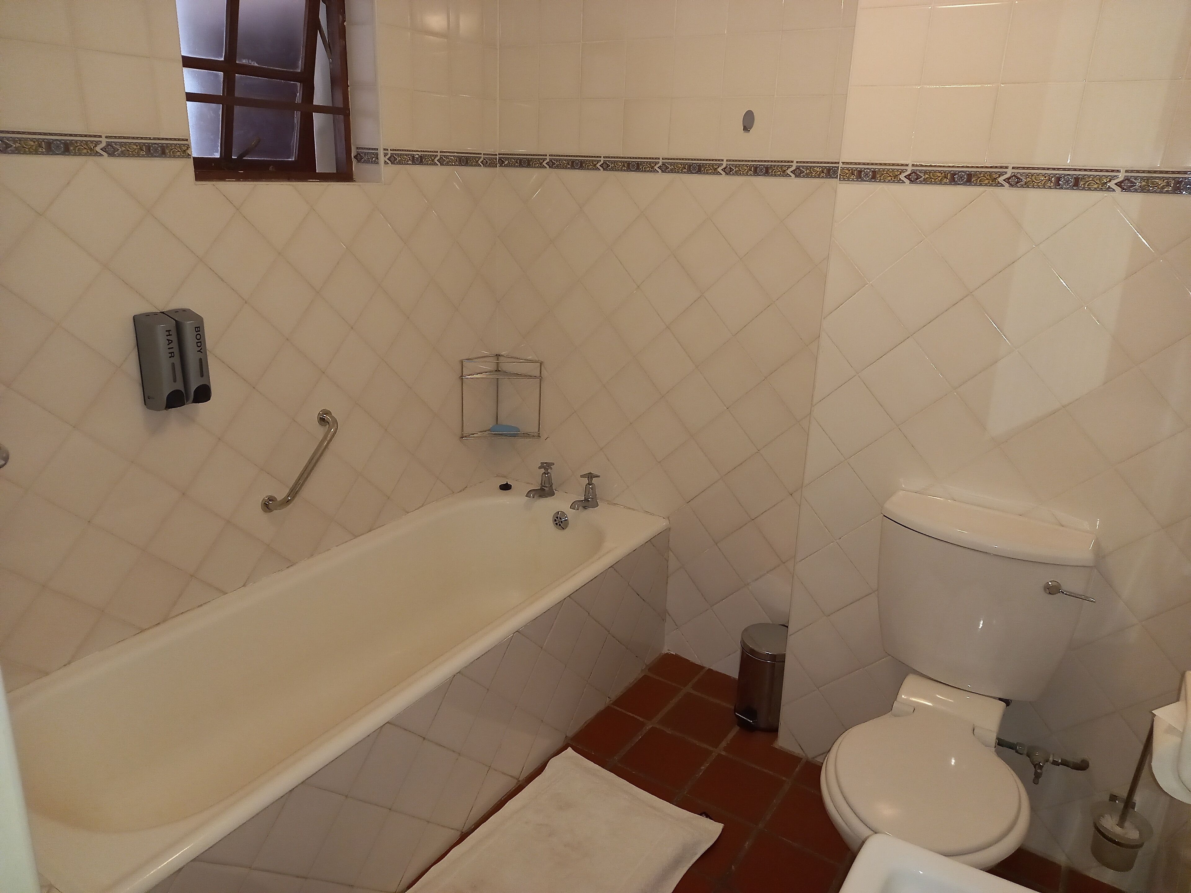 Une salle de bain avec une baignoire, des toilettes et une petite poubelle.