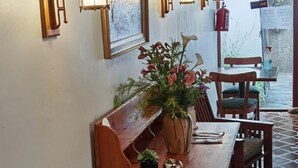 A wooden dining table with chairs, a vase with flowers, and wall-mounted lanterns. - 137 High Street Guest House (Makhanda)
