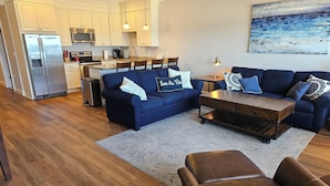 Un salon moderne avec un canapé bleu, un pouf en cuir marron et une table basse en bois.