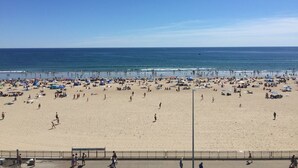 Une plage avec une large promenade, des parasols et des gens qui profitent de la mer.