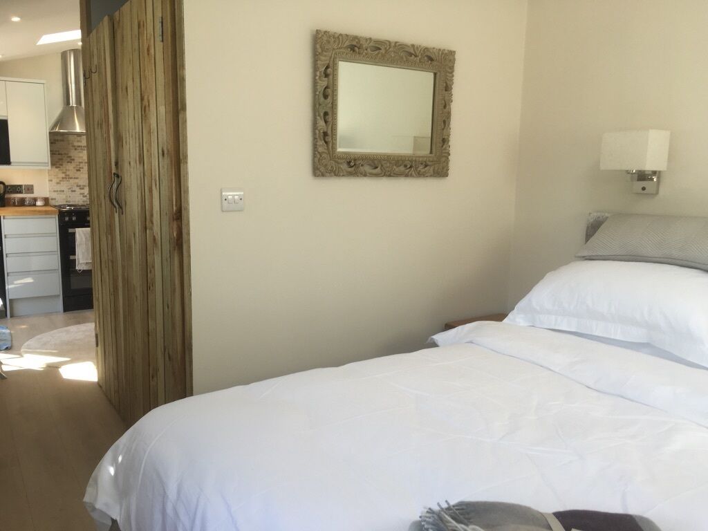 Ein Hotelzimmer mit einem Bett, einem Spiegel, einer Lampe und einer Wandpaneele aus Holz.