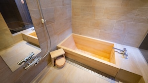 A modern bathroom with a large wooden bathtub, a separate shower area, and a small wooden stool. - Mibu-Juku (Kyoto)
