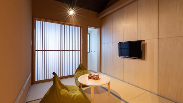 A traditional Japanese room with tatami flooring, a low table, and a television mounted on the wall. - Mibu-Juku (Kyoto)