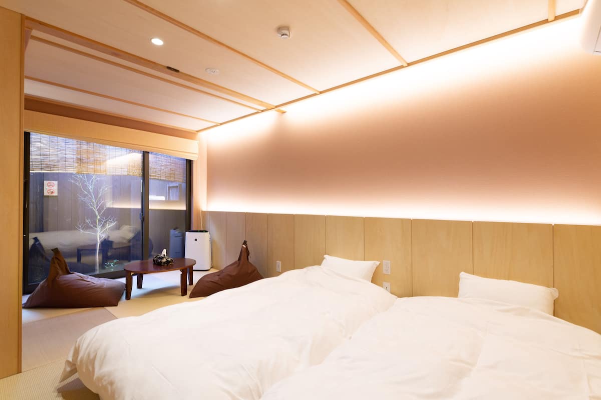 Une chambre d’hôtel moderne avec un grand lit, une petite table et un coin salon agrémenté de coussins.