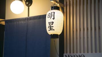 A hanging lantern with Japanese characters, a blue curtain, and a sign reading "MYOJO".