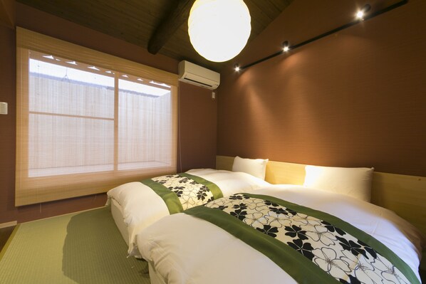 Una habitación de hotel con una cama grande, una ventana con persianas, un equipo de aire acondicionado y un accesorio de iluminación en el techo.