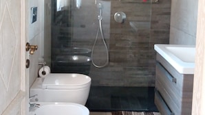A modern bathroom with a glass-enclosed shower, two sinks, and a toilet.