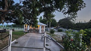 A gazebo with a metal roof and white walls, surrounded by a concrete pathway and metal railings. - Treasure Beach Inn and Bar Room #1: Driftwood Queen (St. Elizabeth Parish)