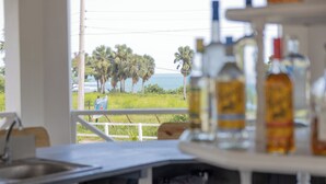 A kitchen with a view of palm trees and the ocean. - Treasure Beach Inn and Bar Room #1: Driftwood Queen (St. Elizabeth Parish)